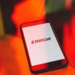 A close-up view of a smartphone showing an error message against a vibrant red background, symbolizing tech issues.